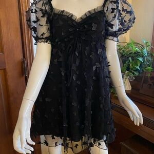 Black babydoll minidress with butterfly appliqués.